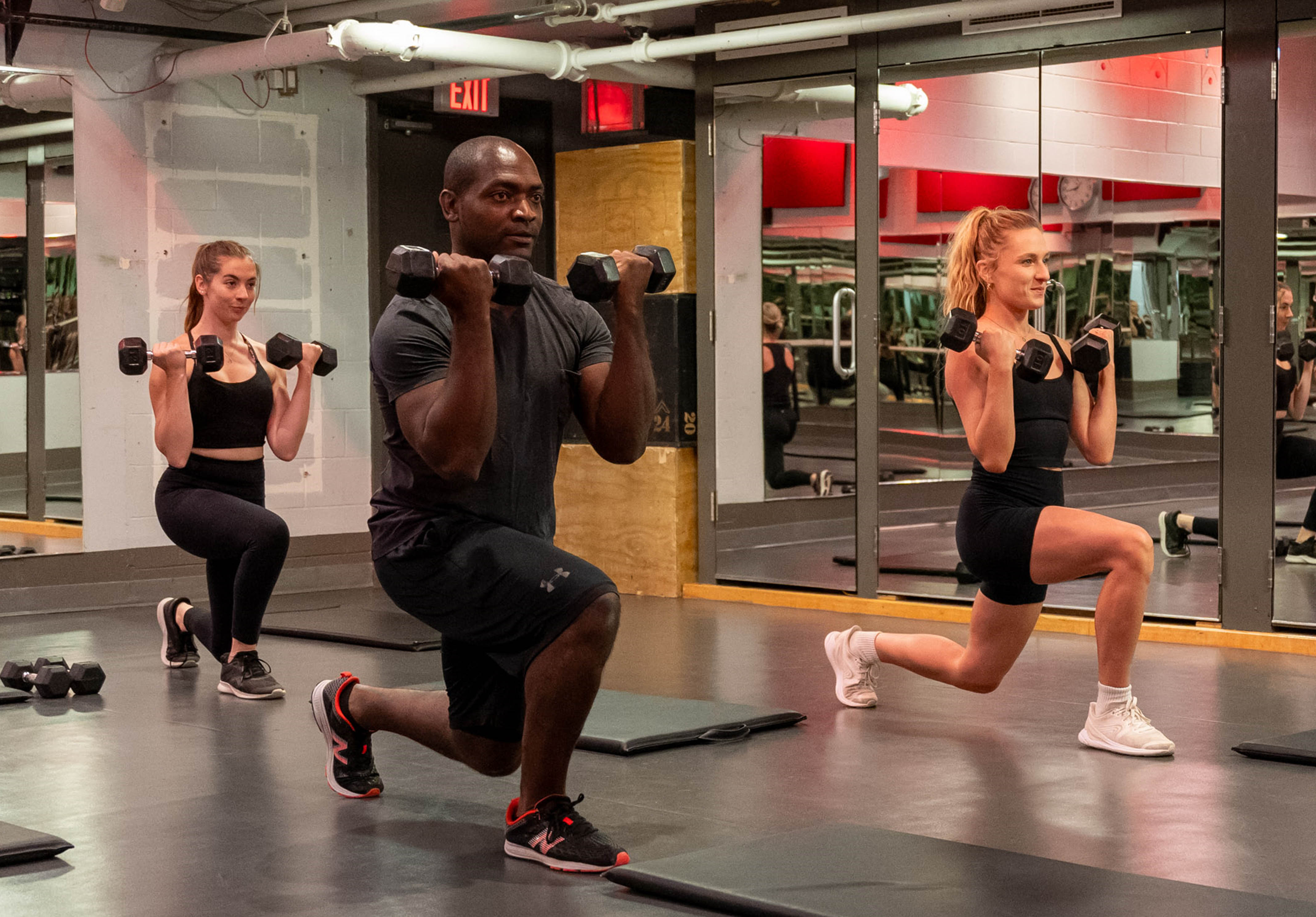 3 young, fit people - 2 women and 1 man - participating in a HIIT Strong group fitness workout in the Adelaide Club's Power Studio